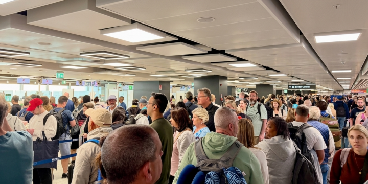EES airport assistance: a Royal Airport Concierge greeter escorts a U.S. traveler past a biometric EES kiosk at a European airport